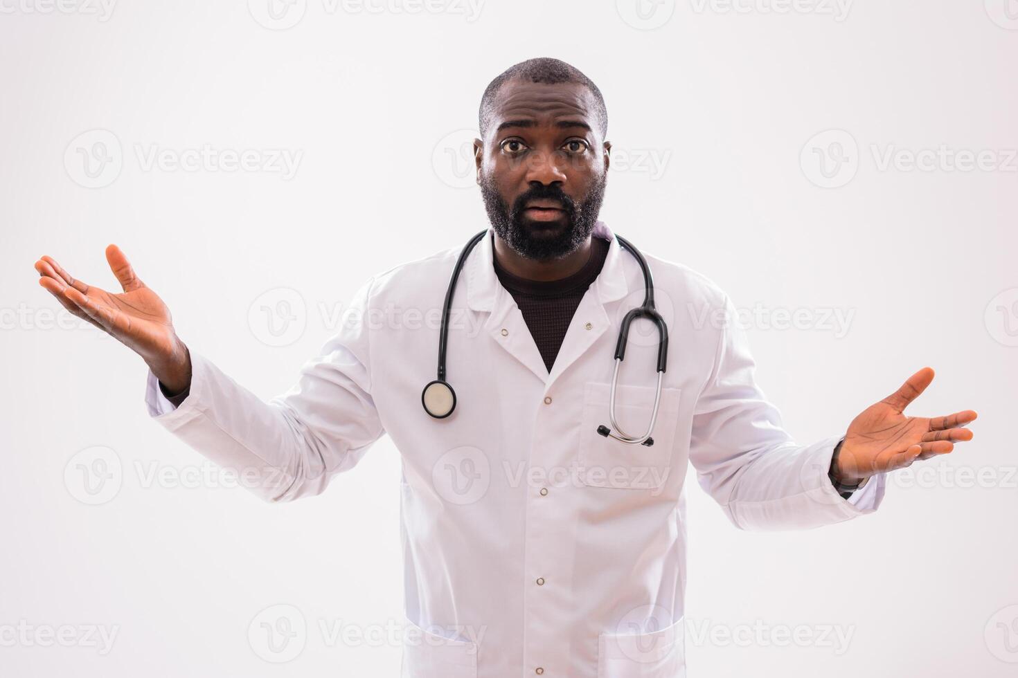 Portrait of serious black male healthcare worker with worried and confused expression gesturing on gray background. photo