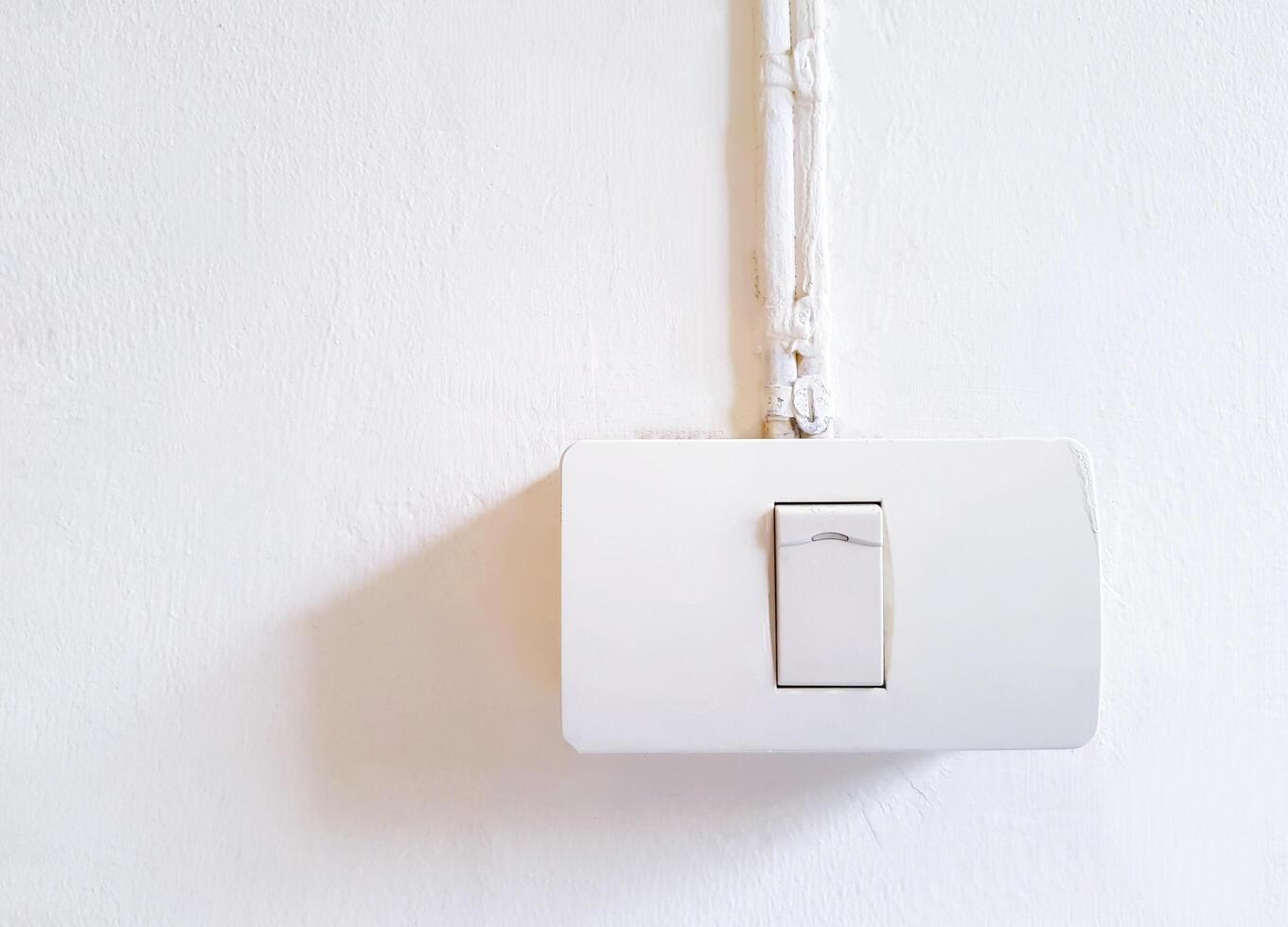 White light switch with cable installed on white wall background and copy space. Control lighting on and off in house or home. photo