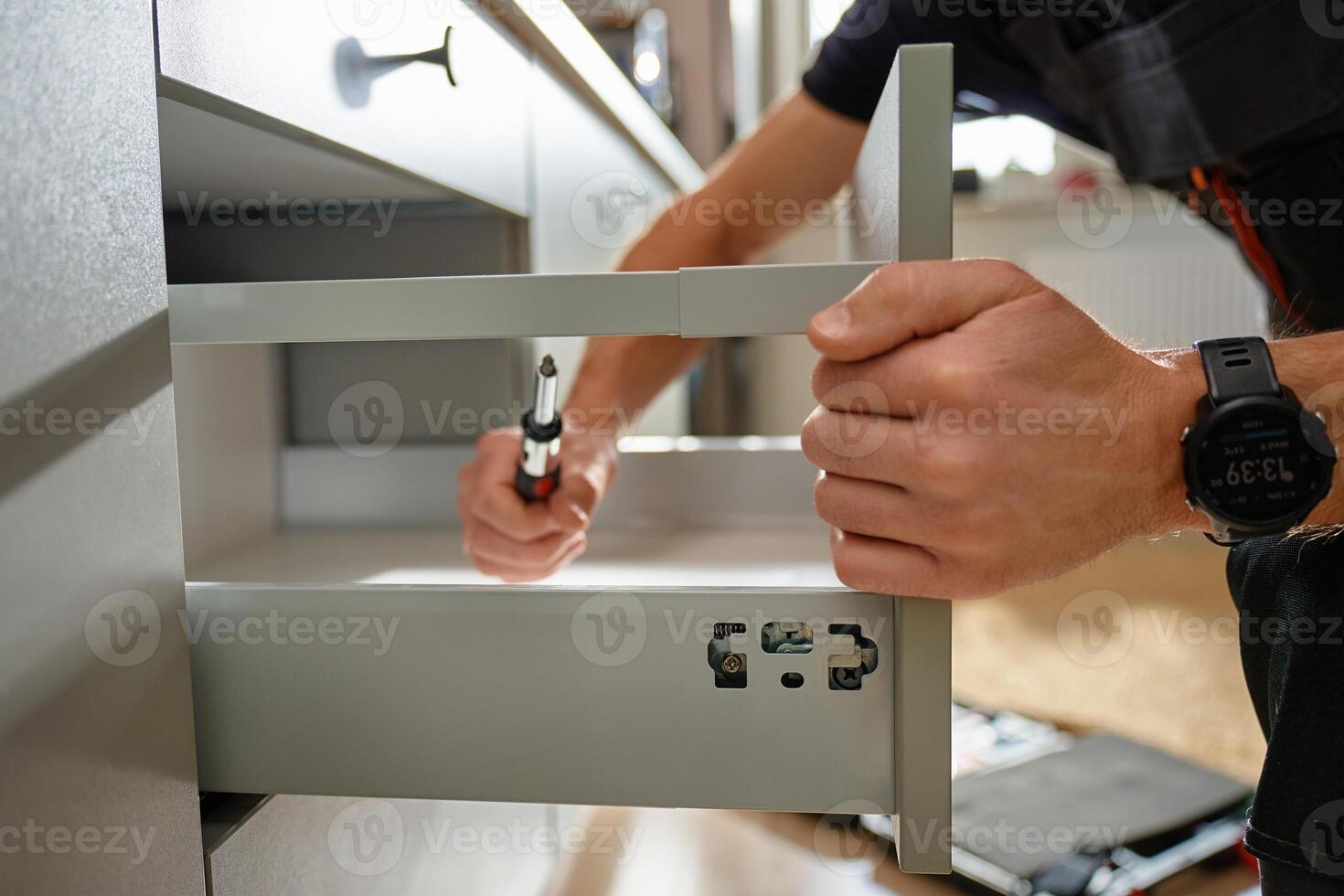 Carpenter installing drawer front in modern kitchen cabinet photo