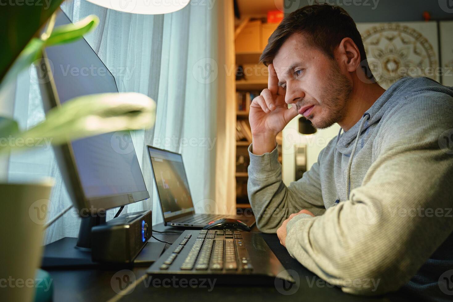 Man procrastinating at workplace while browsing on computer. Freelancer distracted at home offic photo
