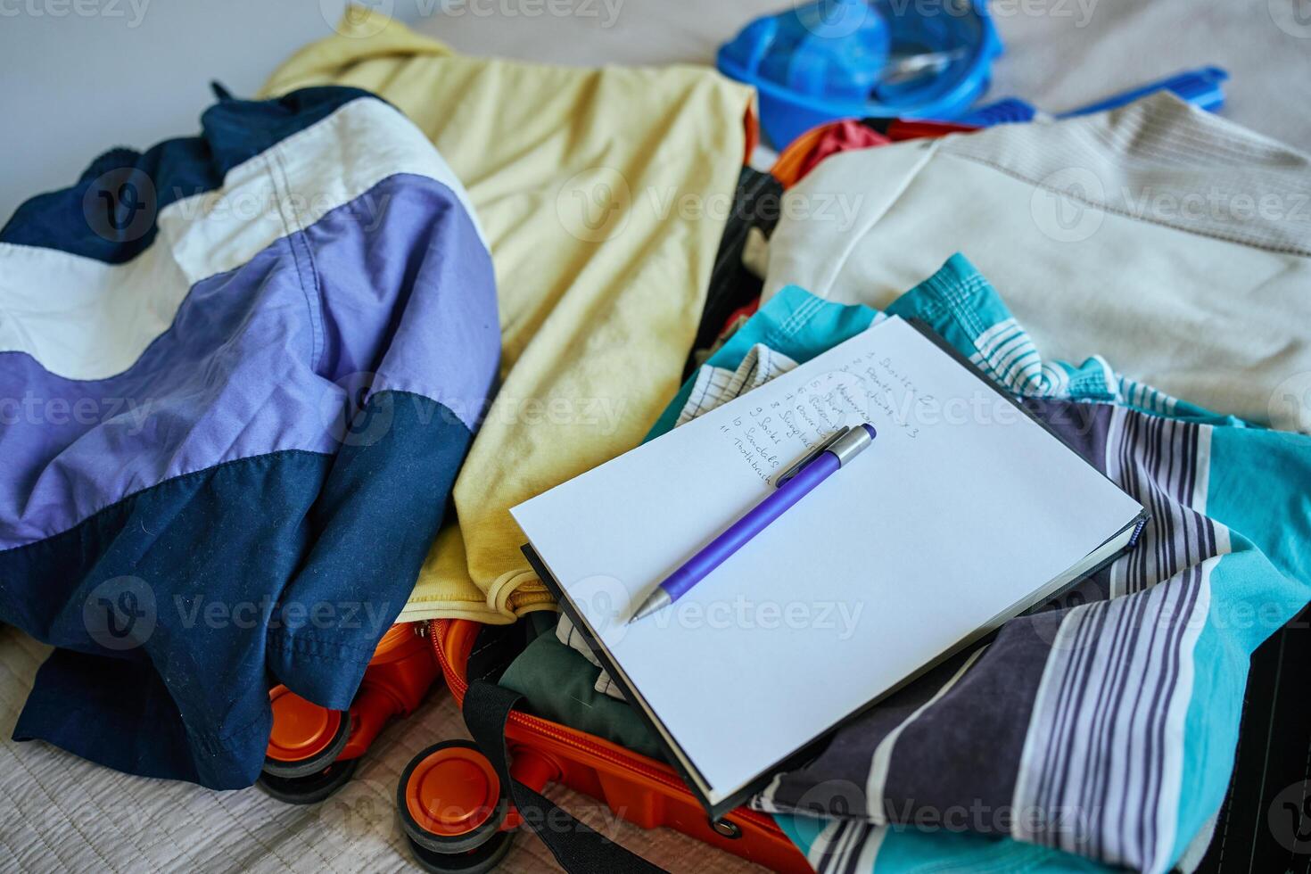 Open suitcase with clothes and packing checklist, preparing for travel photo