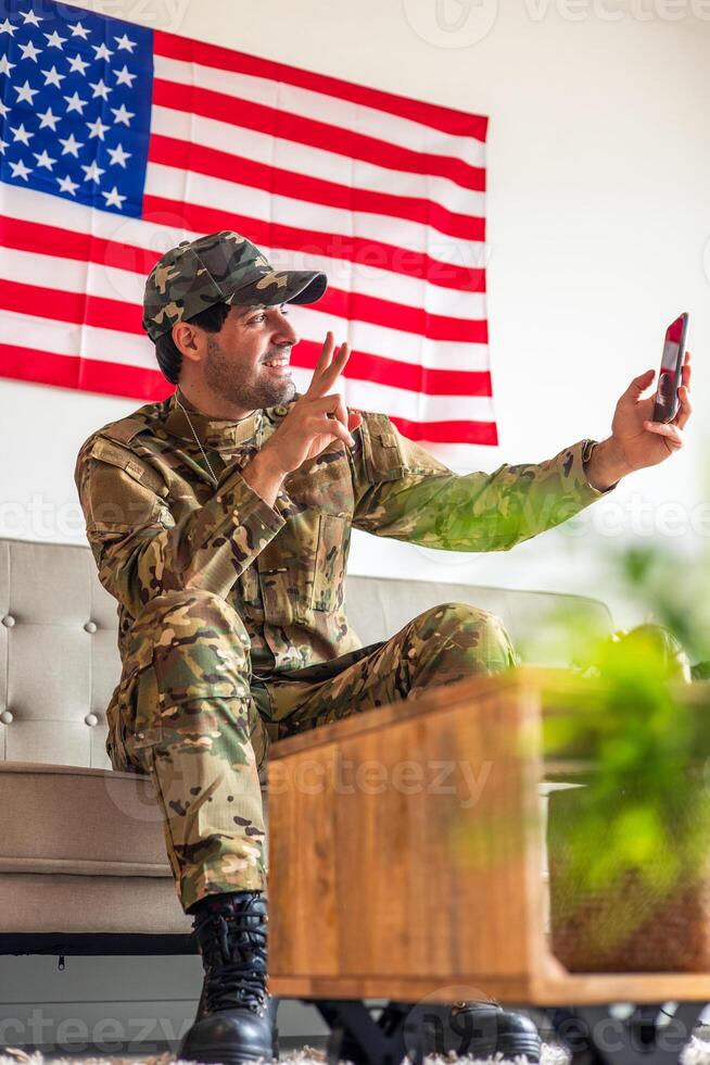 American soldier making call with United States flag in background photo