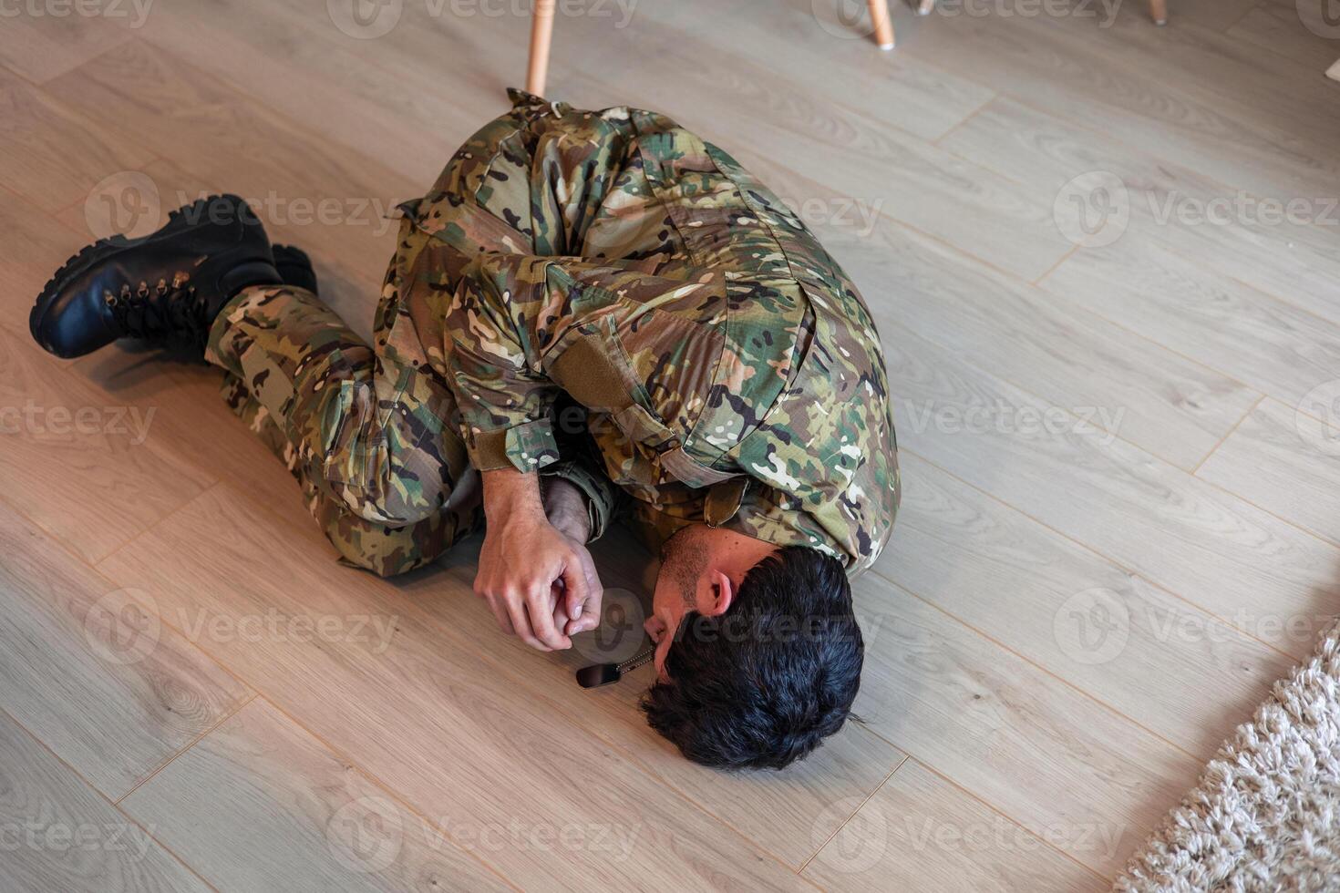 Depressed soldier suffering from post-traumatic stress disorder lying on floor photo