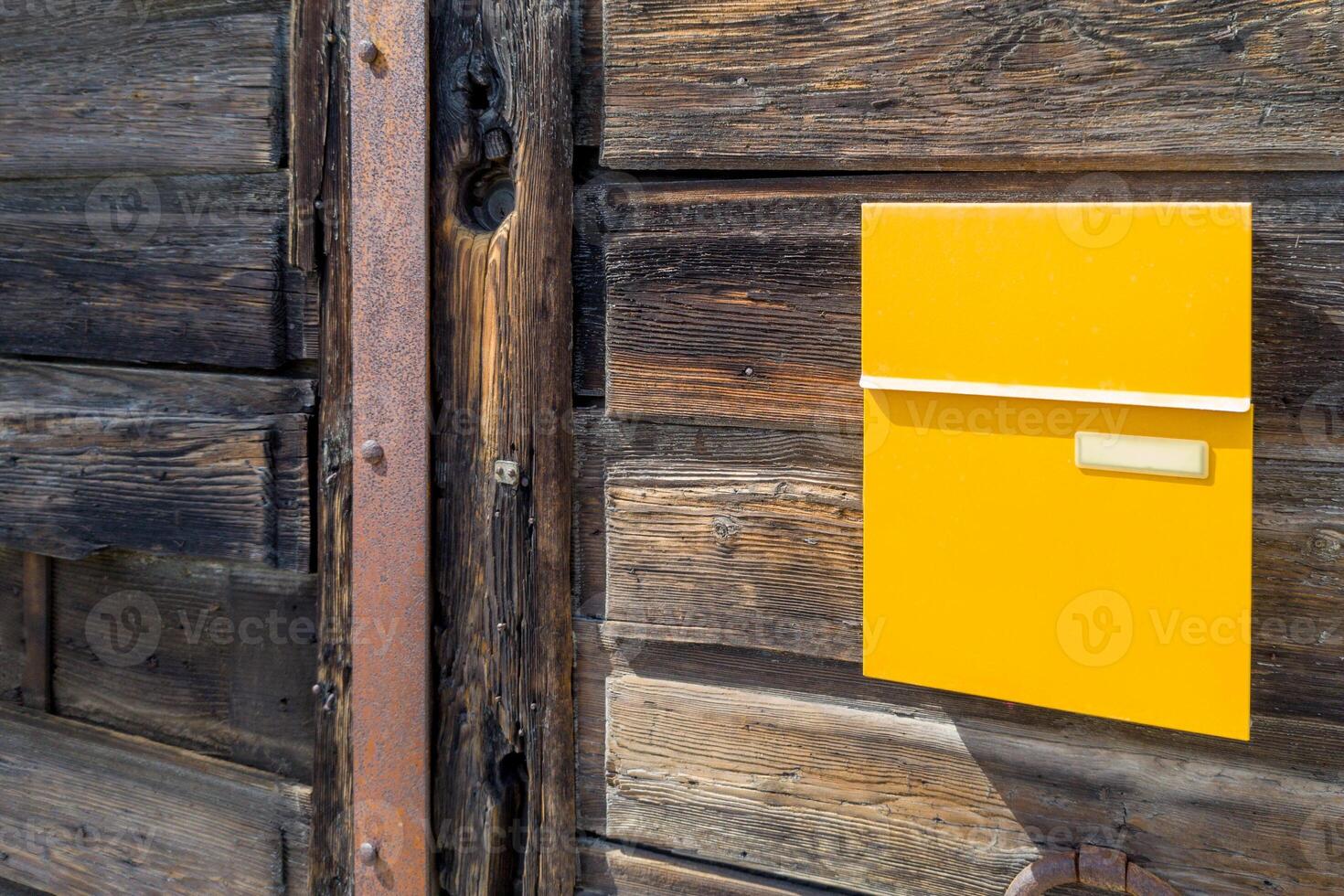 Bright Yellow Mailbox on Rustic Wooden Wall photo