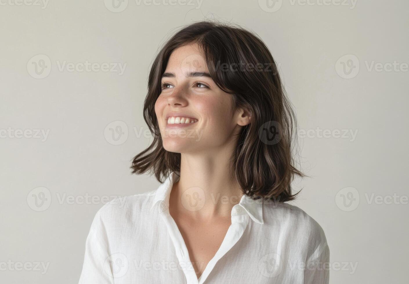 Portrait of a Happy Young Woman with Short Brown Hair Smiling Joyfully Against a Neutral Background photo