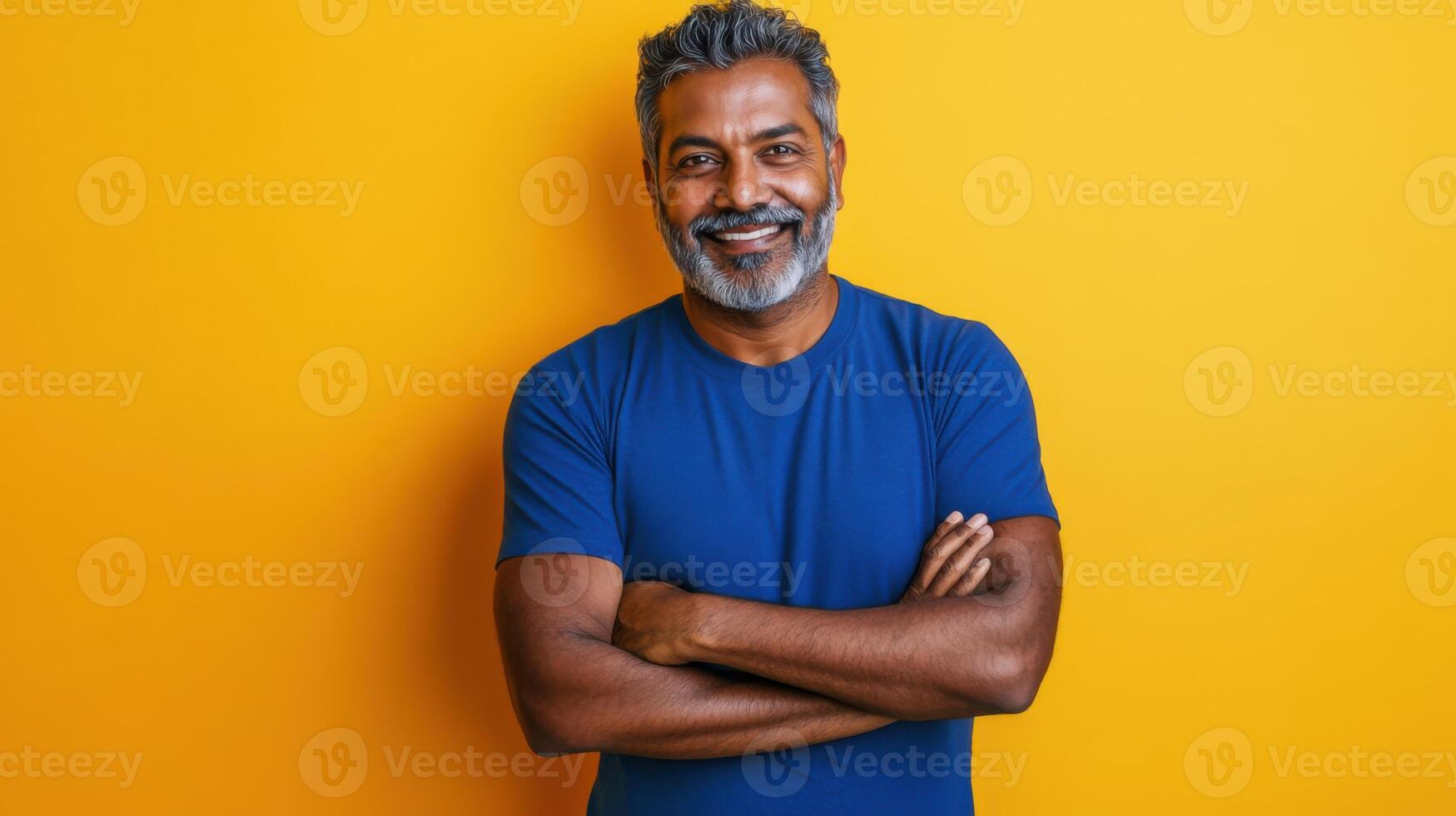 Portrait of a happy indian man standing against a yellow background photo