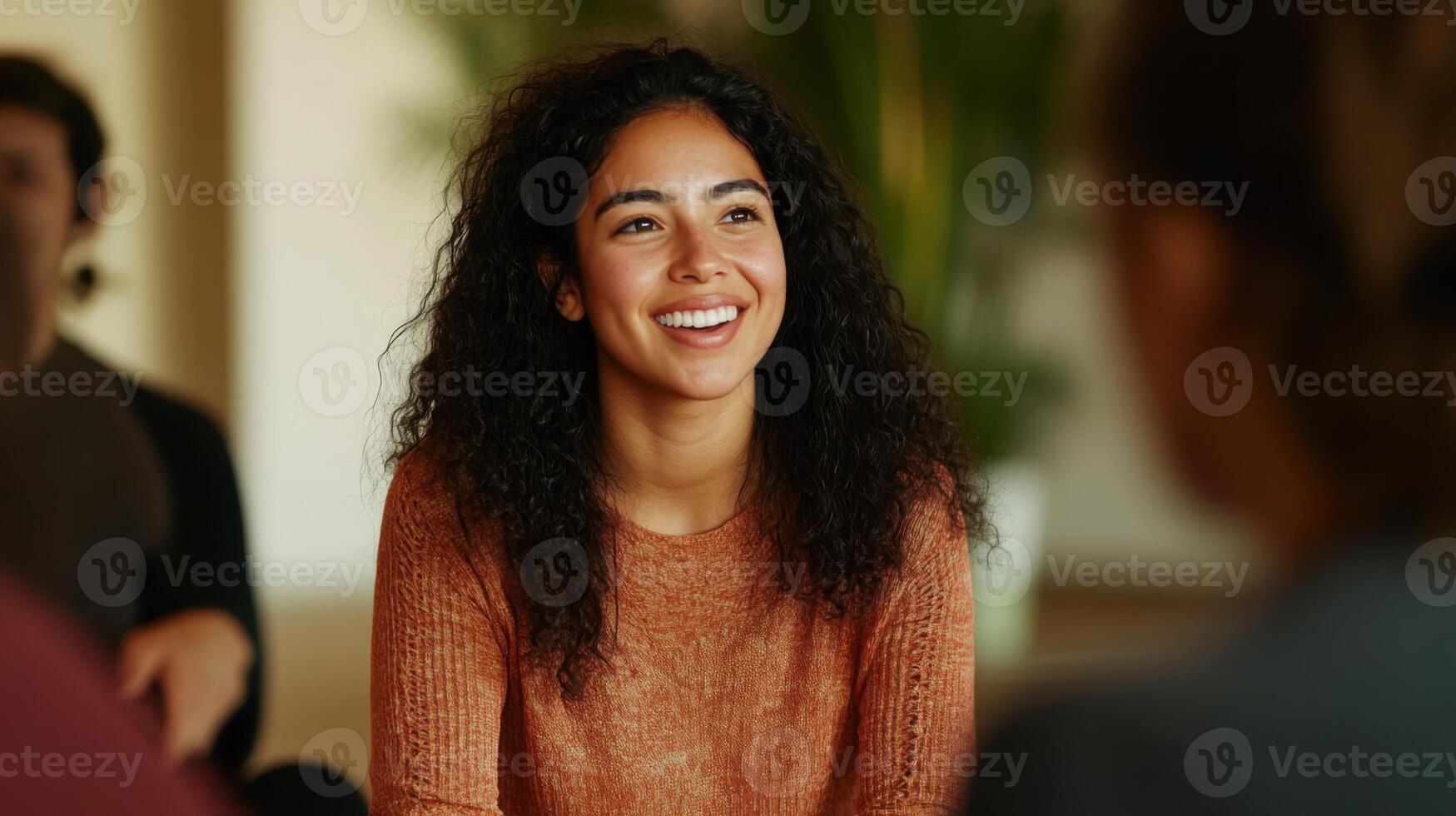 A Portrait of a Happy Young Woman with Curly Hair Smiling Joyfully in a Group Setting photo