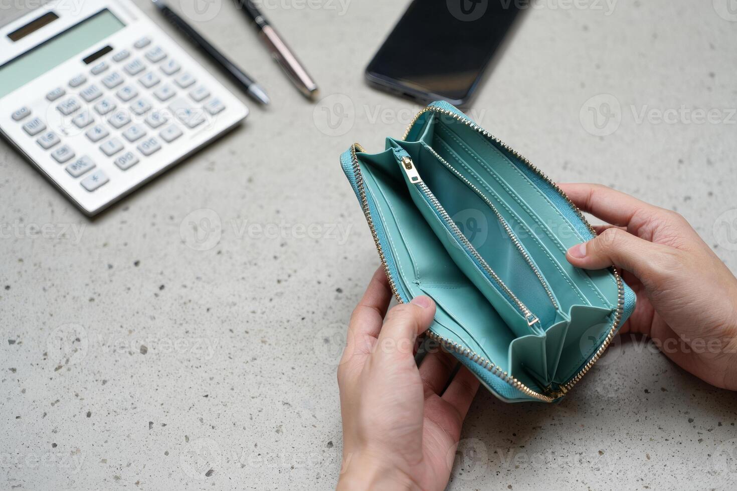A person holding an empty wallet next to a calculator photo