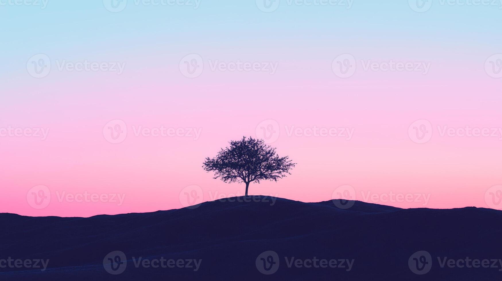 A lone tree stands on top of a hill in front of a pink and blue sky photo