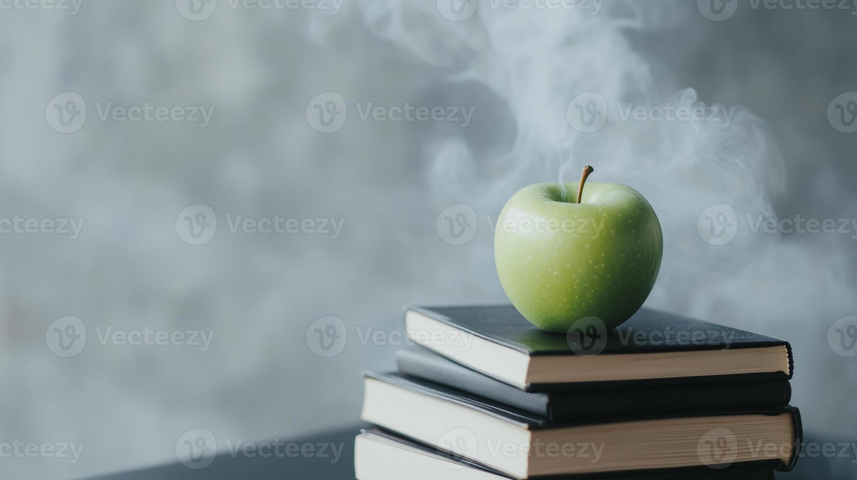 An apple sits on top of a stack of books photo