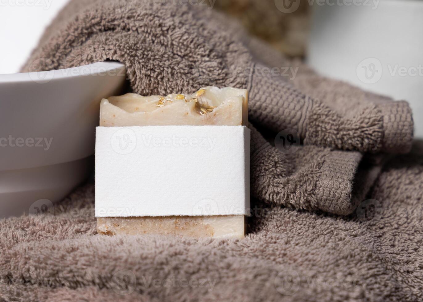 Soap bar with blank label on a brown towels near vessel sink in bathroom closeup, mockup photo