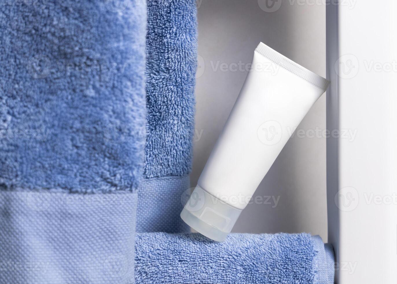 White cream tube on blue towel on a bathroom shelf, close up, cosmetic mockup photo