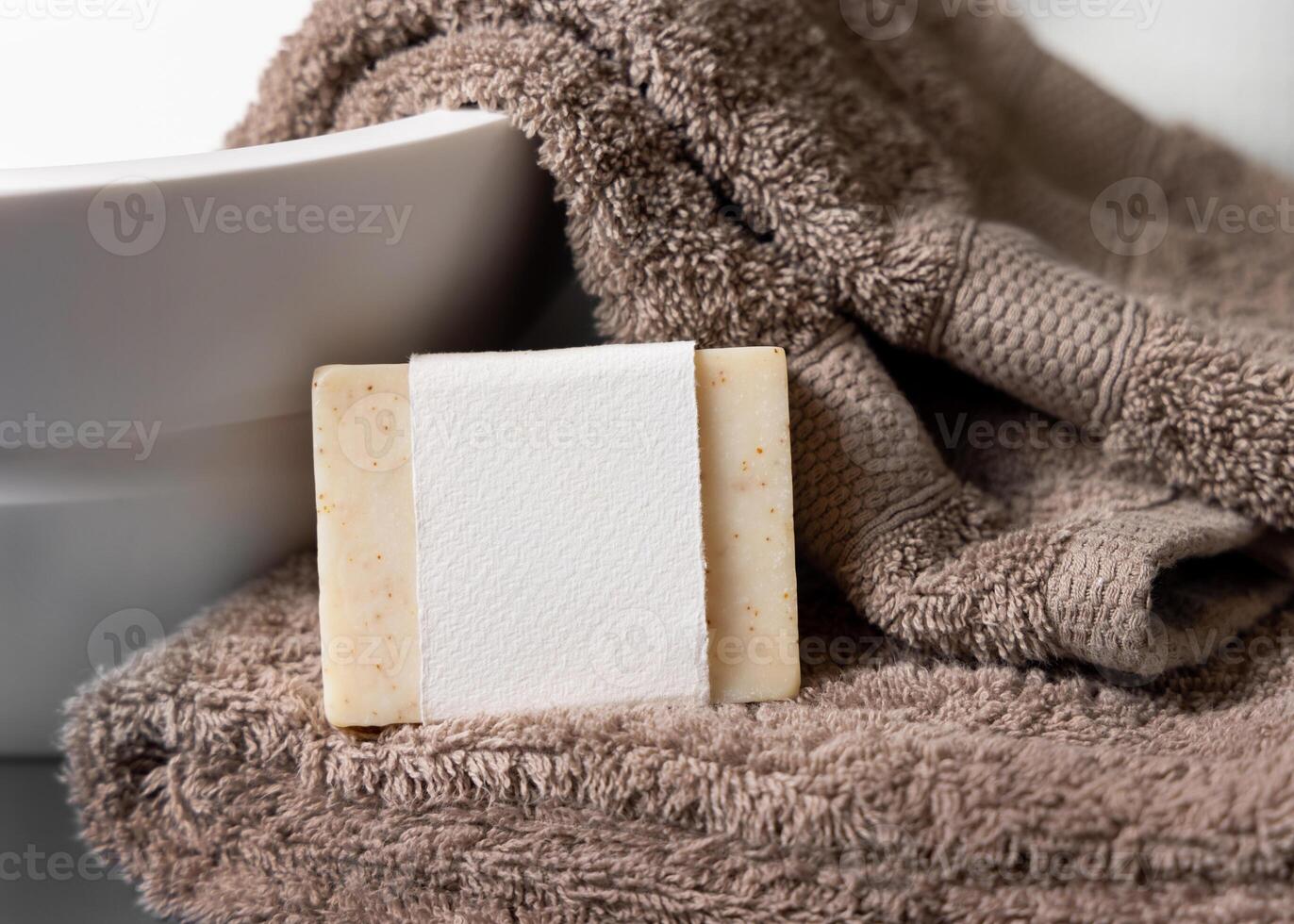 Soap with a label on light brown towels near vessel sink in bathroom closeup, mockup photo