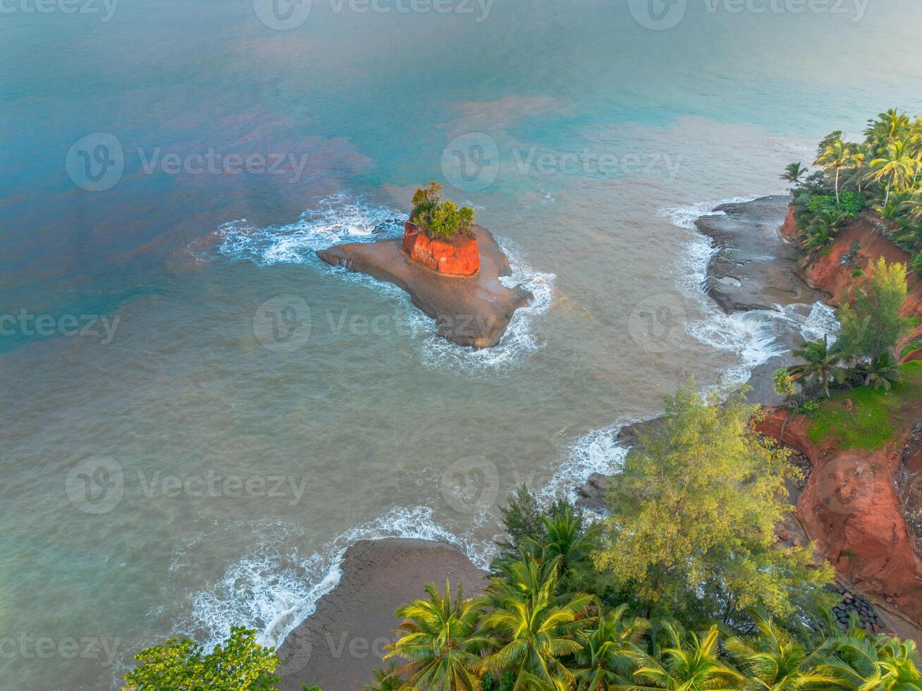 An aerial view of a beach with a red rock photo