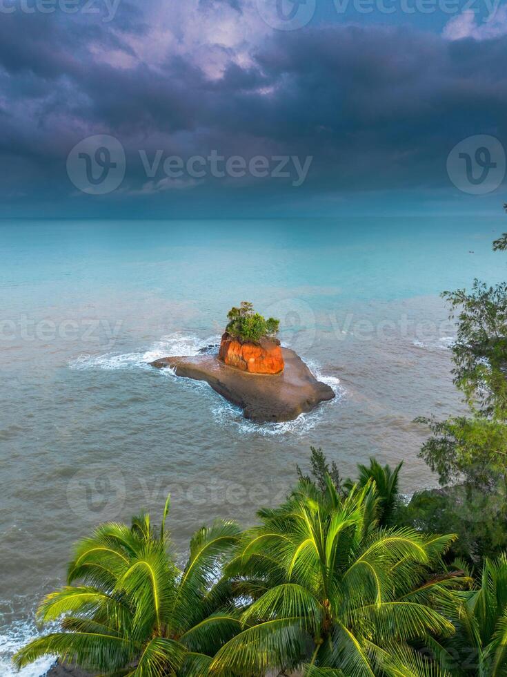 A small island surrounded by palm trees on a cloudy day photo