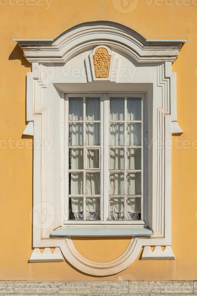 Historic window design on a vibrant yellow building at Peterhof demonstrating rich architectural detail and elegance photo