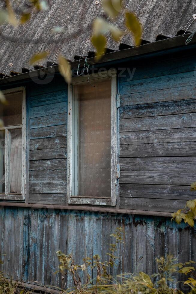 Rustic wooden house with blue paint and weathered exterior located in a serene countryside setting photo