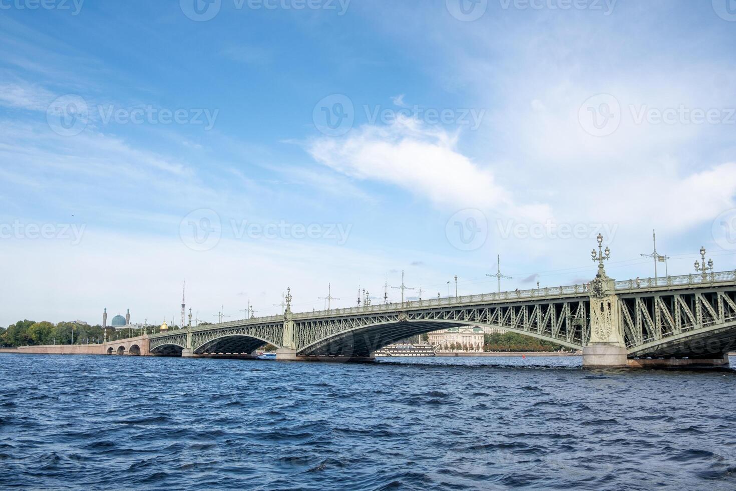 Bridge over the water in Saint Petersburg surrounded by blue sky and trees during daylight photo