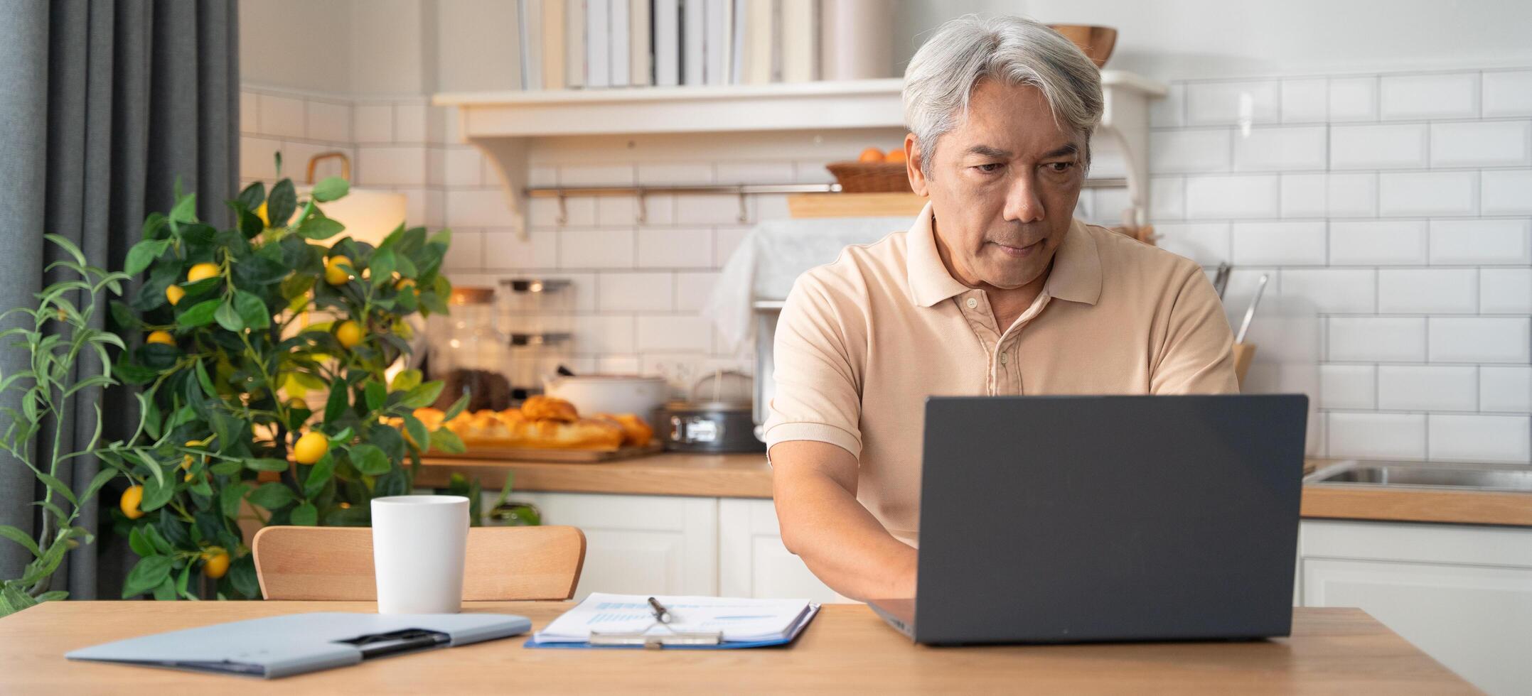 Asian senior man learning with laptop in the morning at home photo