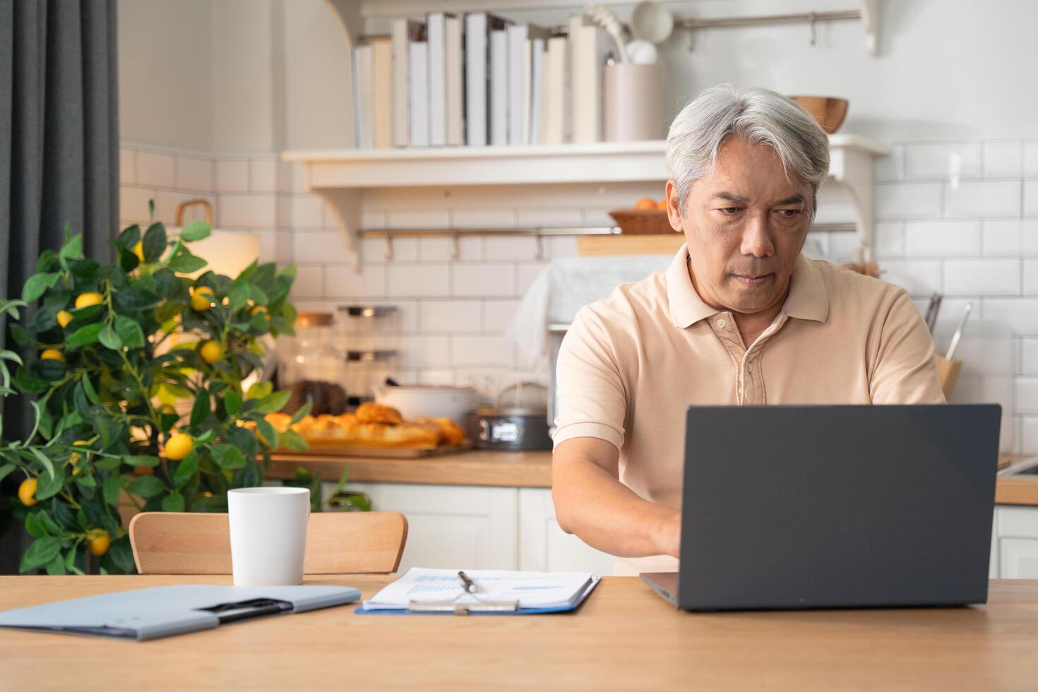 Asian old man learning or working with laptop in the morning at home photo