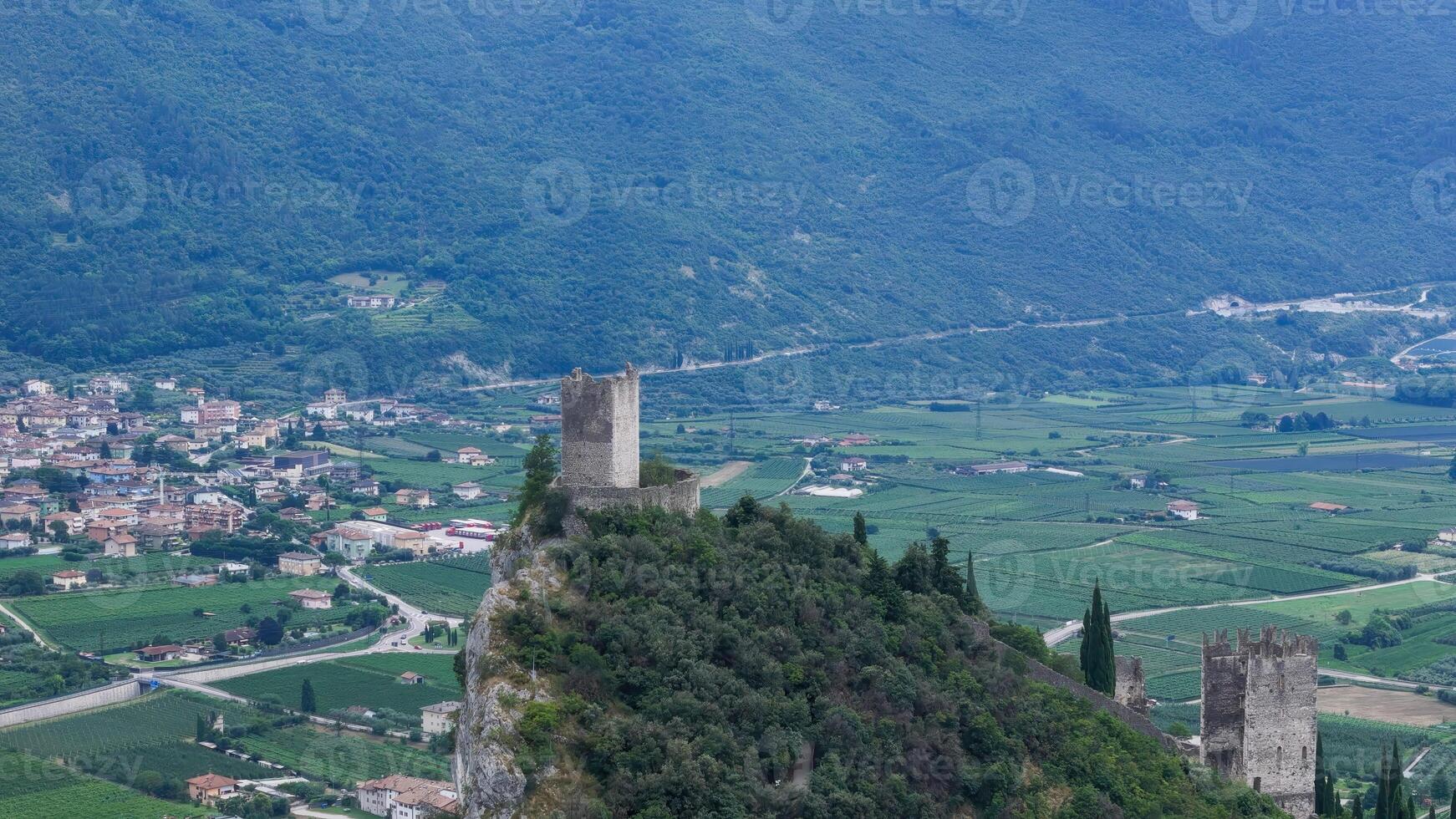 Majestic castle perched on a rocky cliff overlooking a lush valley in Italy during a serene afternoon photo