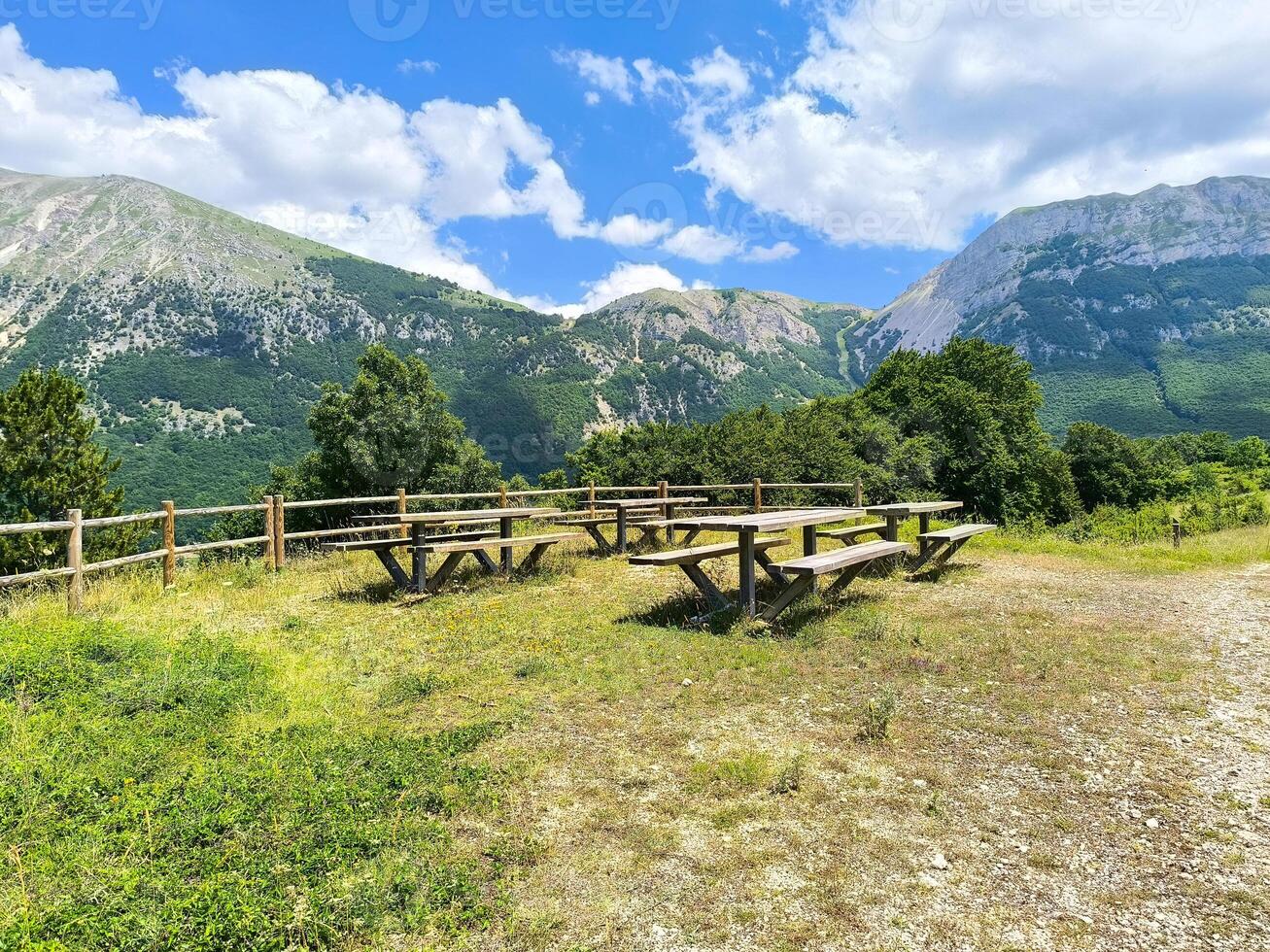 Tranquil picnic area with wooden tables amidst majestic mountains on a sunny day photo