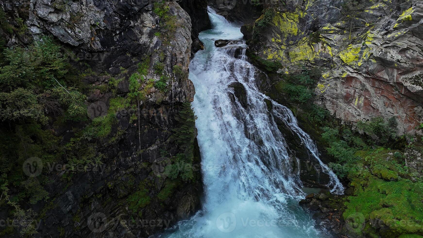 Majestic waterfall cascades down rocky cliffs in a serene forest setting at the heart of nature's untouched beauty photo
