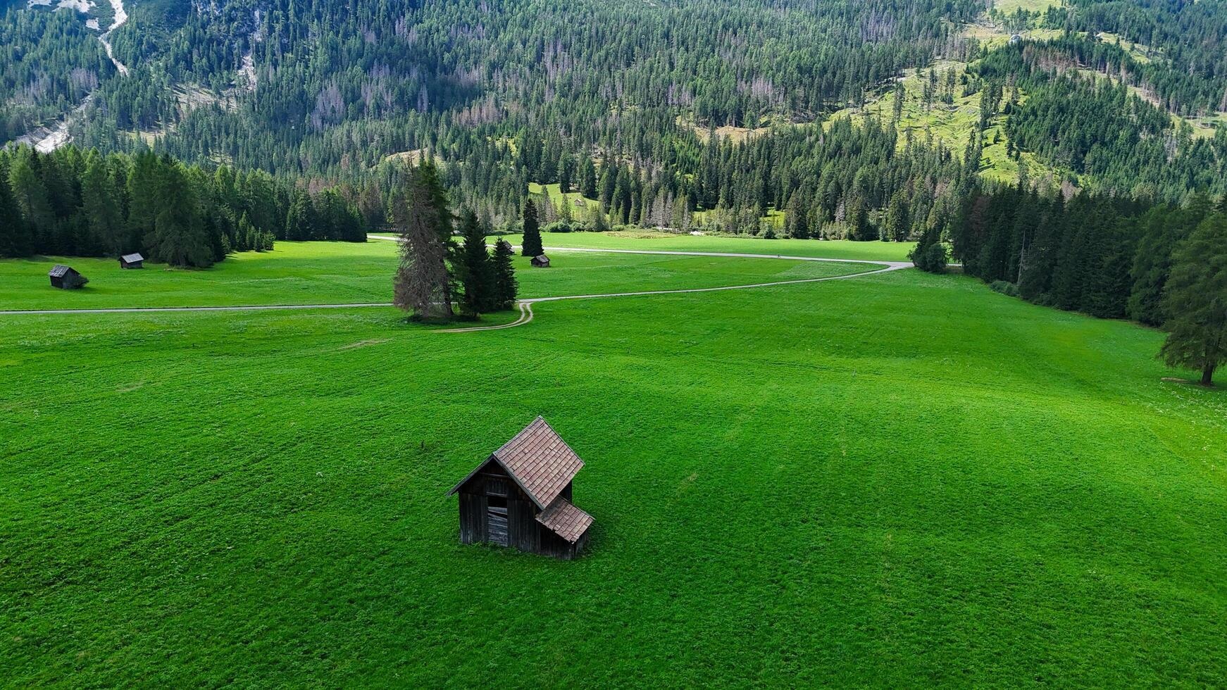 Embracing tranquility in a verdant landscape surrounded by mountains and rustic cabins under a clear blue sky photo