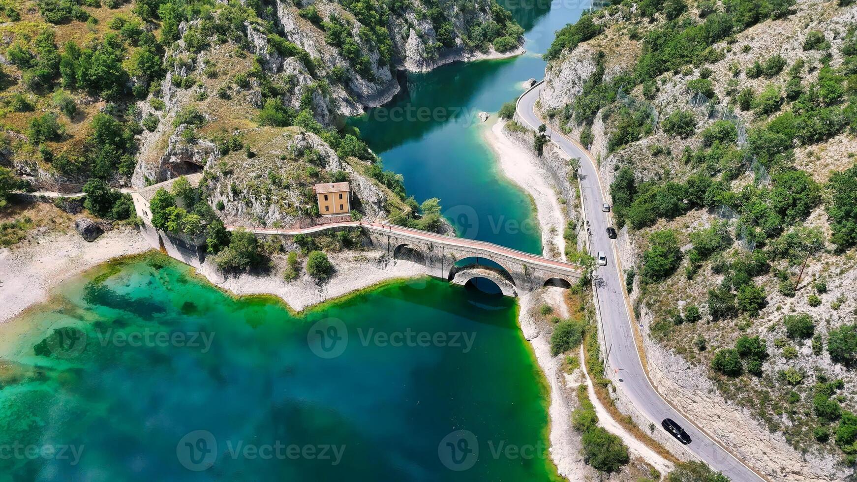 Serene waters and winding roads showcase the beauty of nature around a historic bridge in a remote landscape photo
