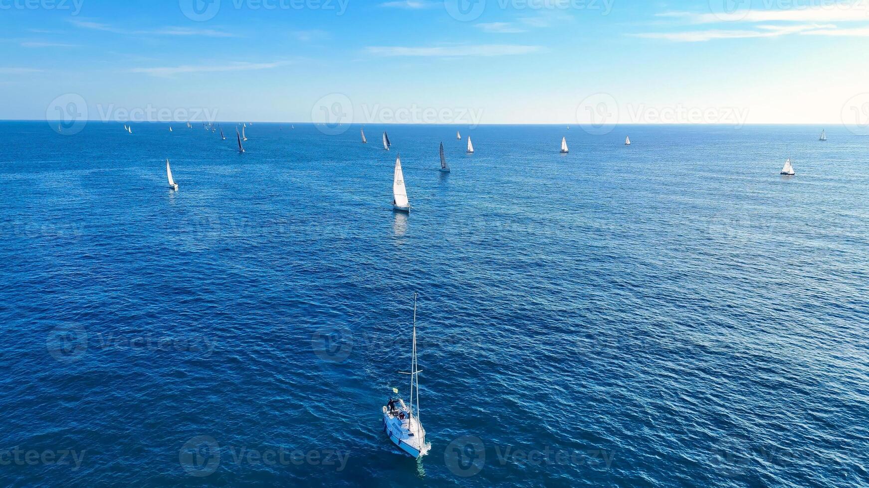 Sailboats gracefully navigate the calm waters under a clear blue sky on a sunny afternoon photo