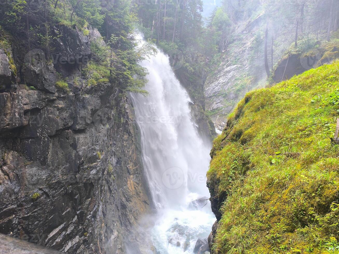 Majestic waterfall cascading through rocky cliffs in a misty forest setting during midday photo