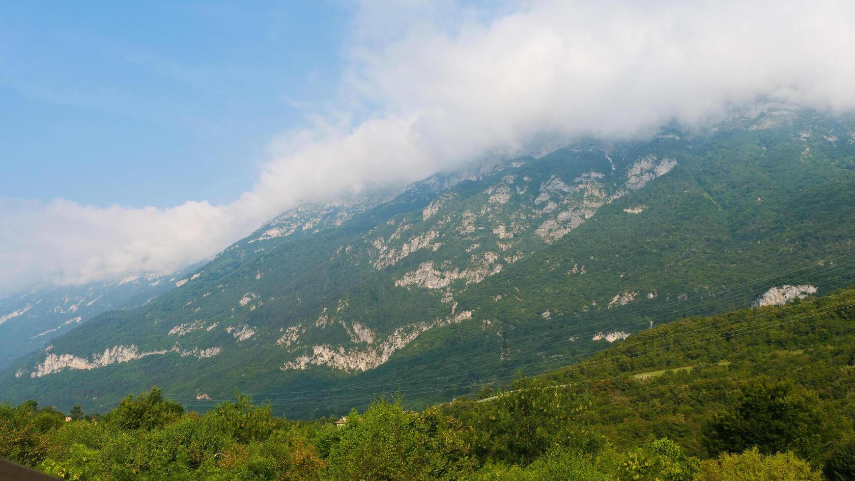 Majestic mountain landscape with lush greenery and misty peaks under a bright blue sky in the heart of nature's serenity photo