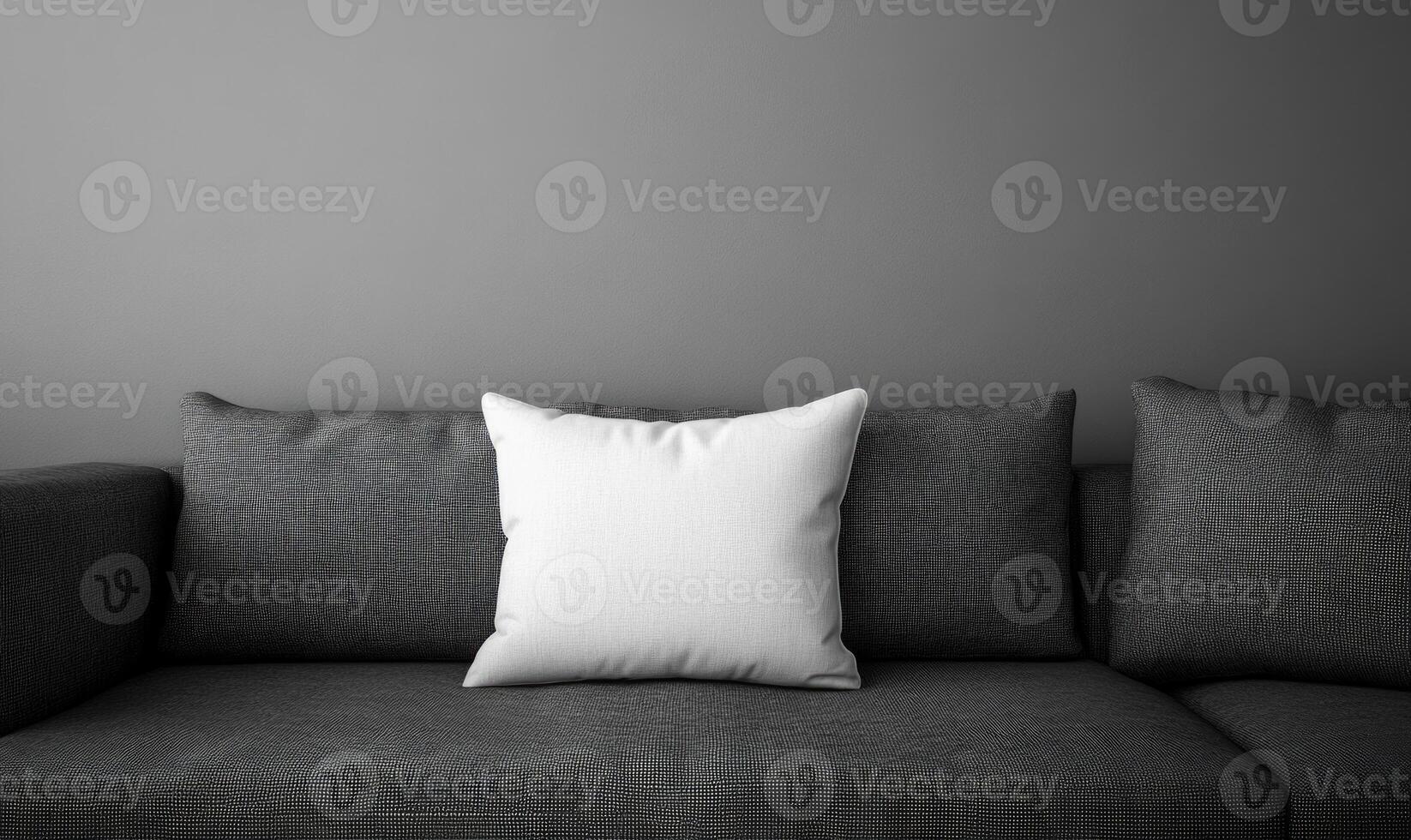 a white pillow on a gray couch in front of a wall photo