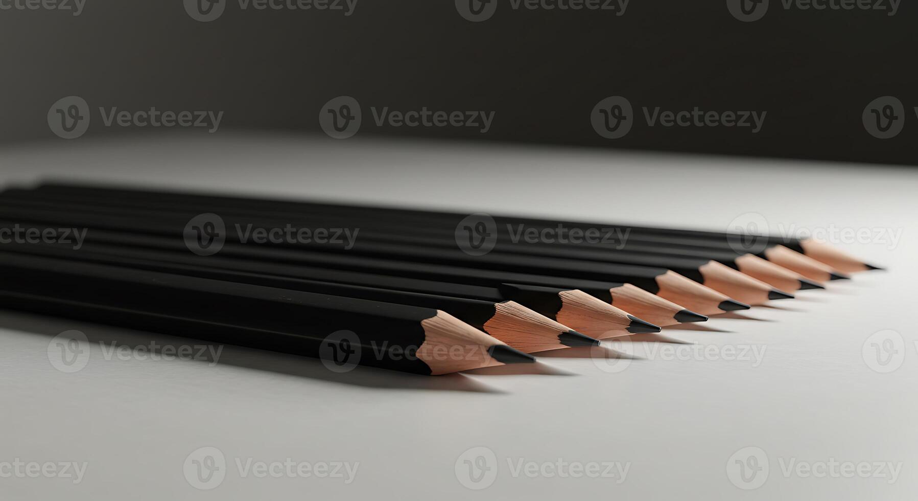Arrangement of Sharpened Black Pencils on a Light Surface with Dark Backdrop photo