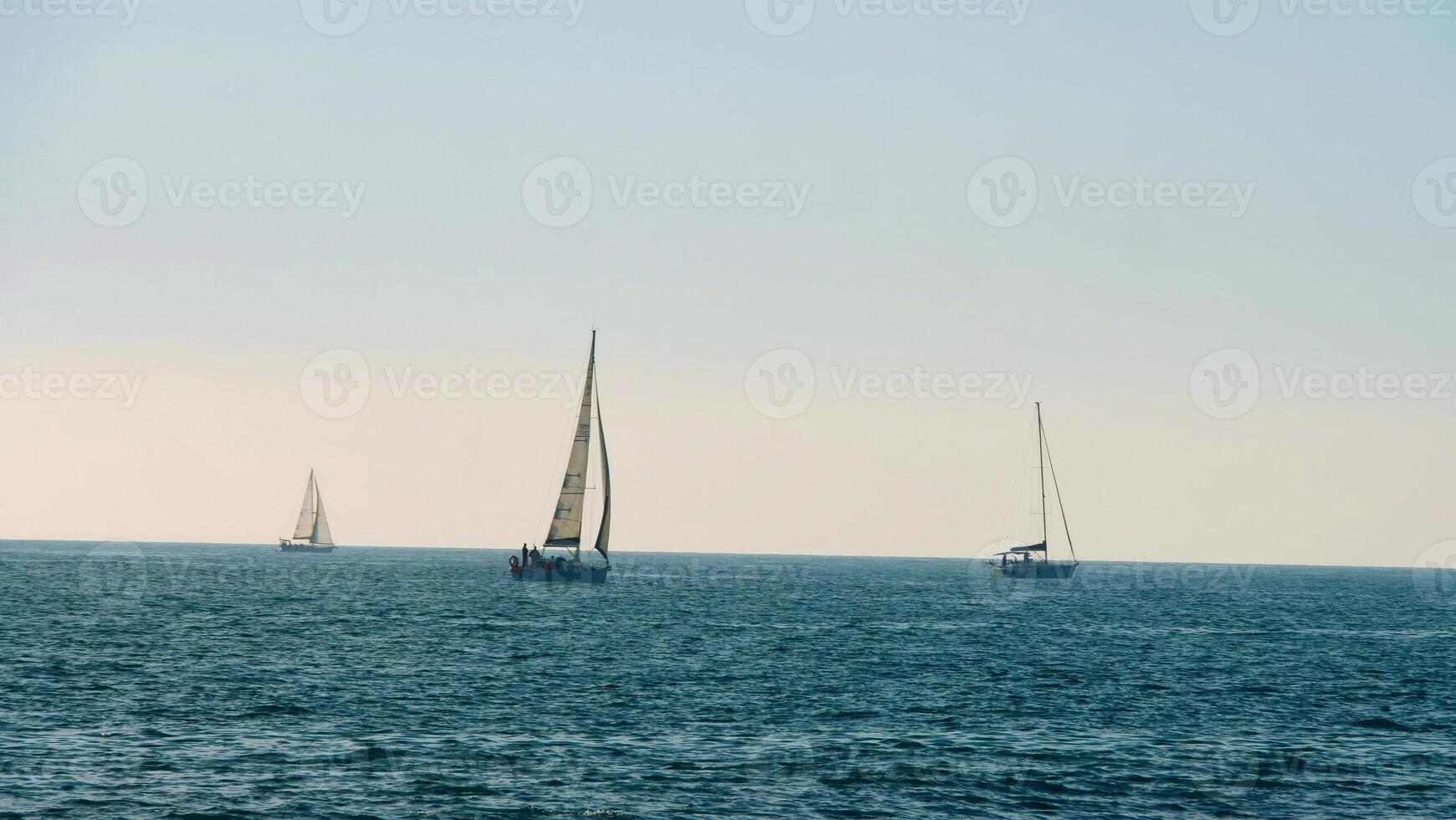 Three sailboats enjoying a calm day at sea photo