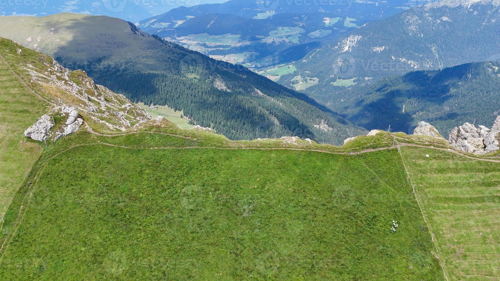 Expansive green meadow overlooking majestic mountain ranges in the heart of nature's tranquility at sunrise photo