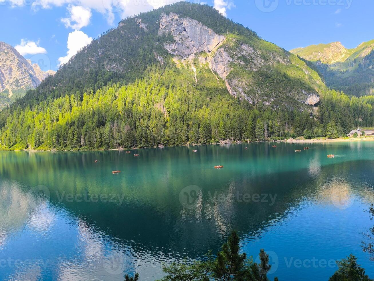 Serene mountain lake reflecting vibrant greenery and blue skies during a sunny summer afternoon photo