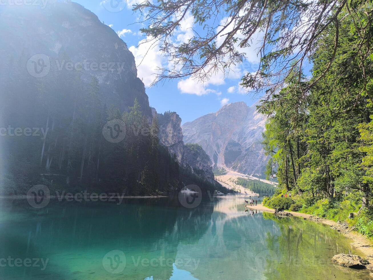 Majestic reflections of mountains and trees in the tranquil waters at a serene lake in the Dolomites during a bright sunny day photo