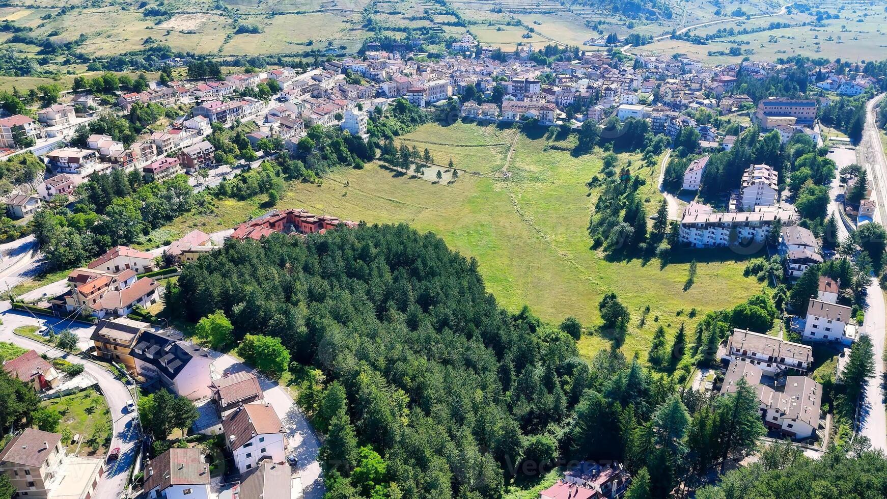 Expansive view of a quaint Italian village nestled among rolling hills and lush greenery photo