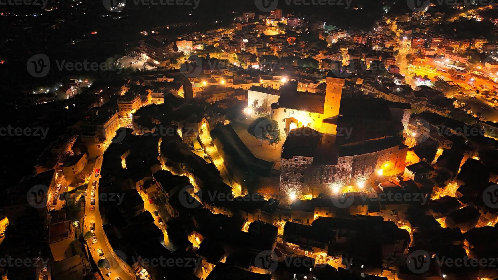 A stunning view of a historic castle illuminated at night, surrounded by a charming village filled with glowing lights photo