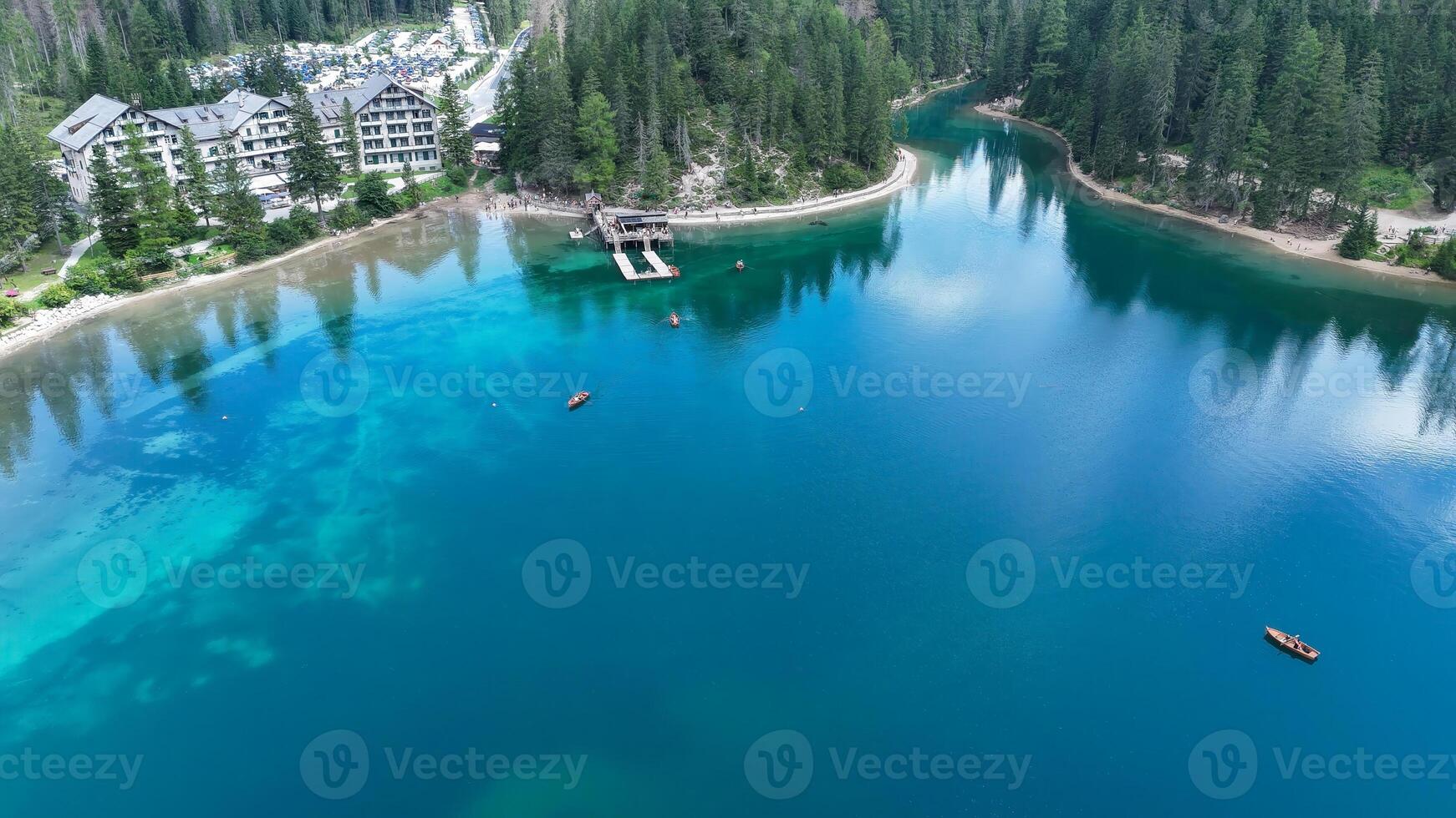 Captivating waters of a serene lake surrounded by towering trees and elegant lodges under a clear blue sky photo