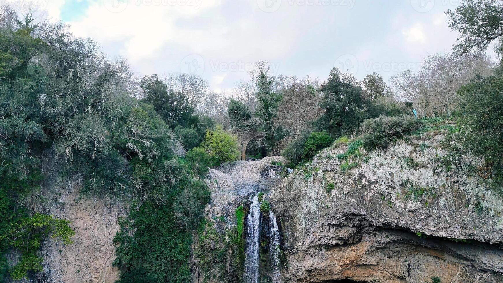 Exploring the hidden beauty of a cascading waterfall nestled within a lush green landscape in the heart of nature photo
