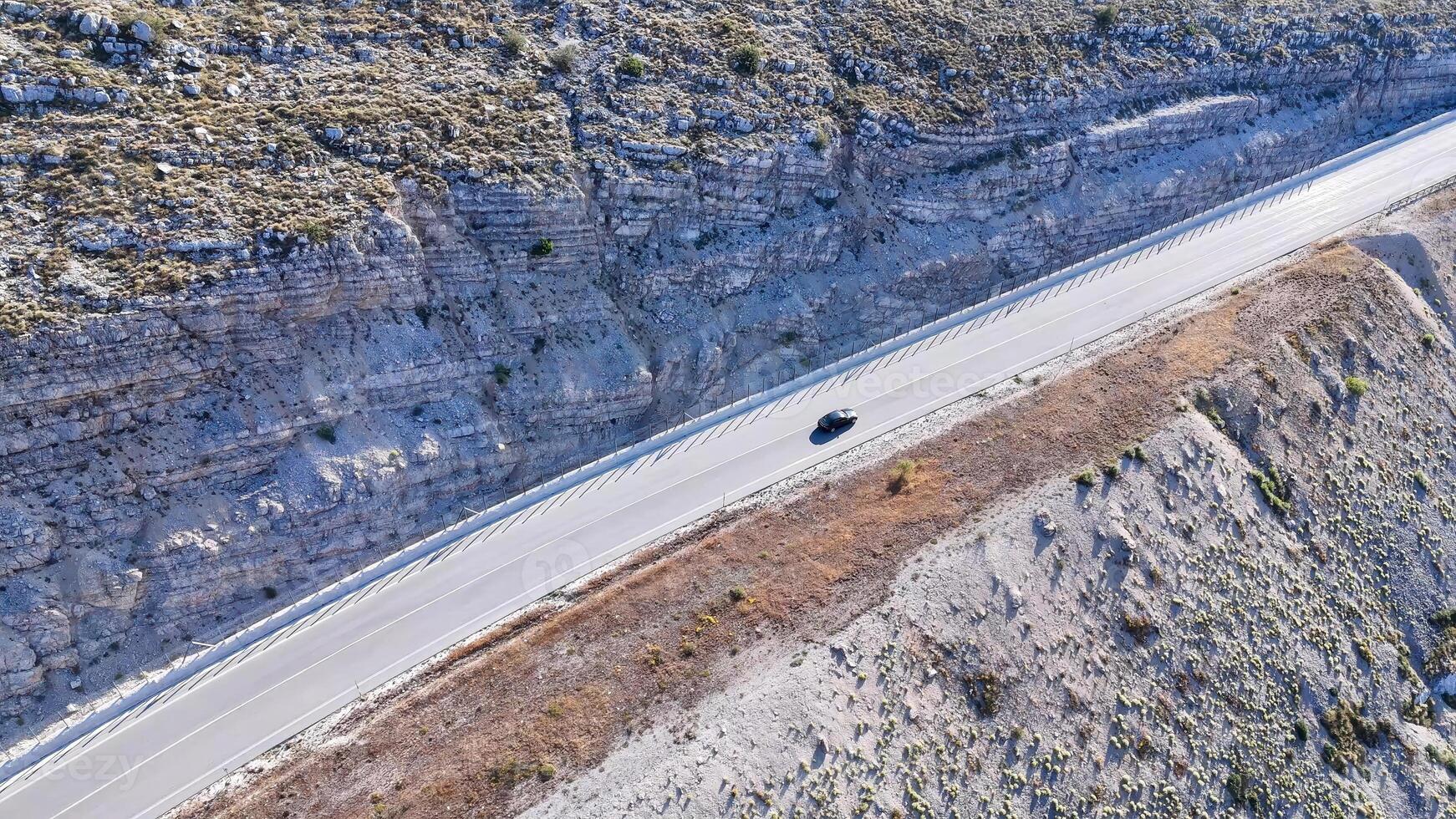 Driving along a rugged mountain road in the heart of nature's breathtaking landscape with rocky cliffs and open skies photo