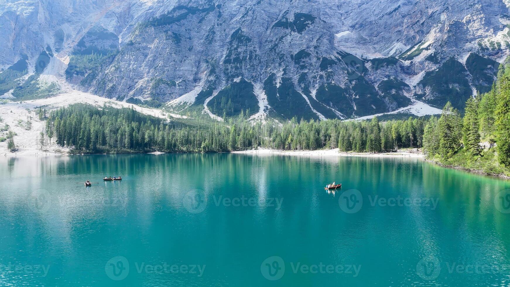 Serenity reigns over a tranquil turquoise lake surrounded by majestic mountains and lush forests on a bright sunny day photo