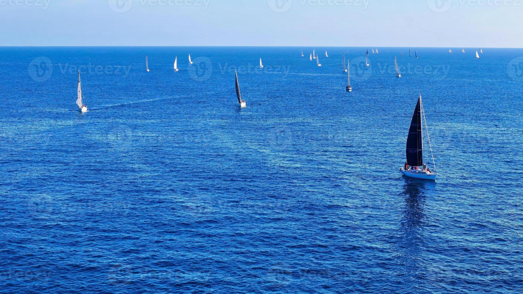 Sailboats glide gracefully across the shimmering blue waters during a serene afternoon in the open sea photo