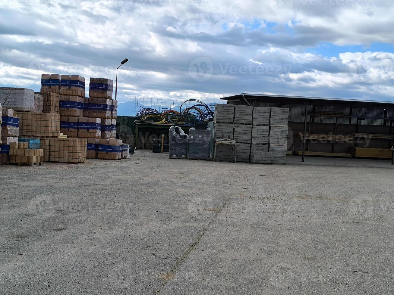 Stacks of building materials and tools under a cloudy sky in a construction yard during the afternoon photo