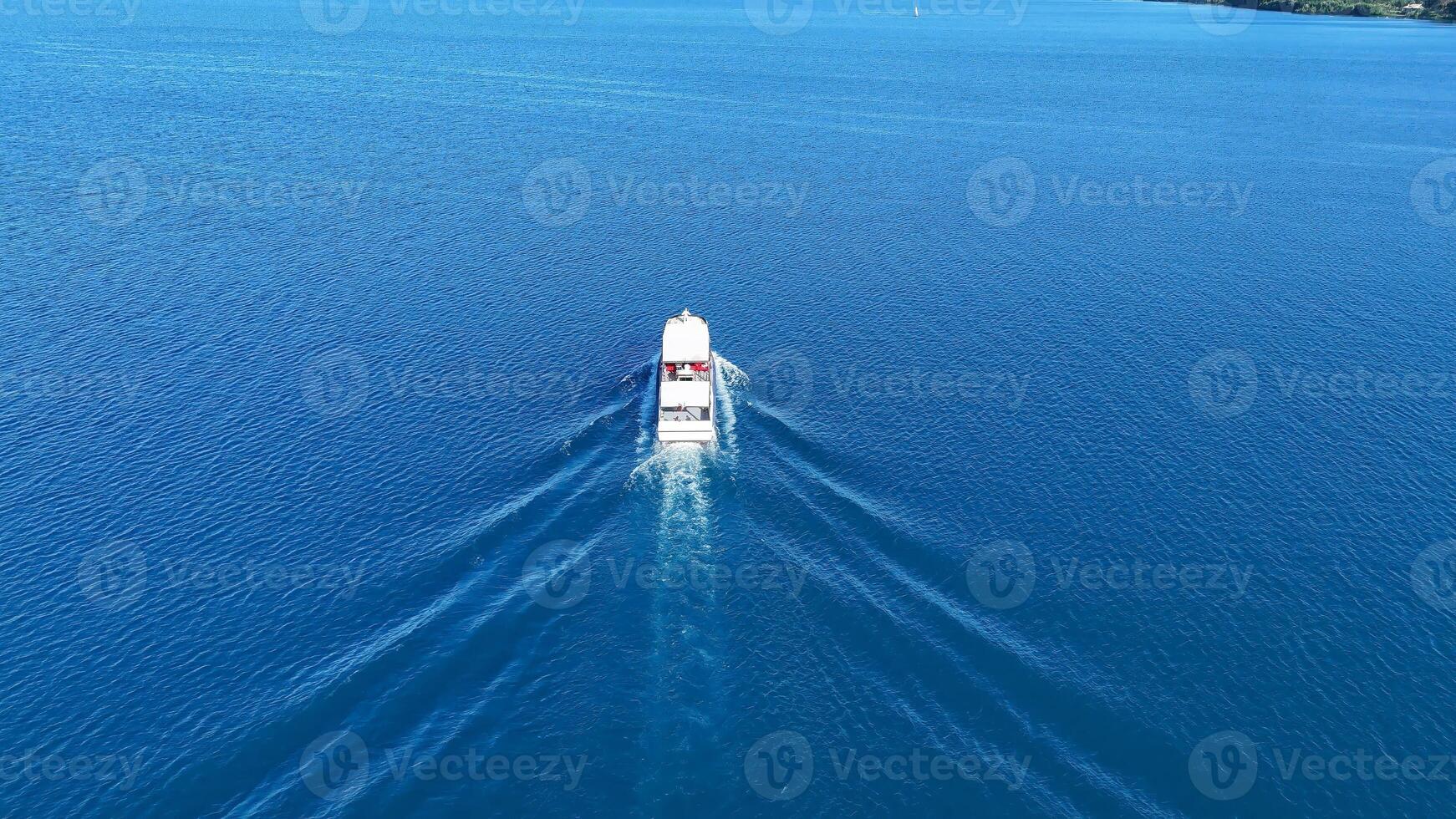 Cruising gracefully across the sparkling blue waters of a serene lake on a sunny day with a boat leaving tranquil ripples behind photo