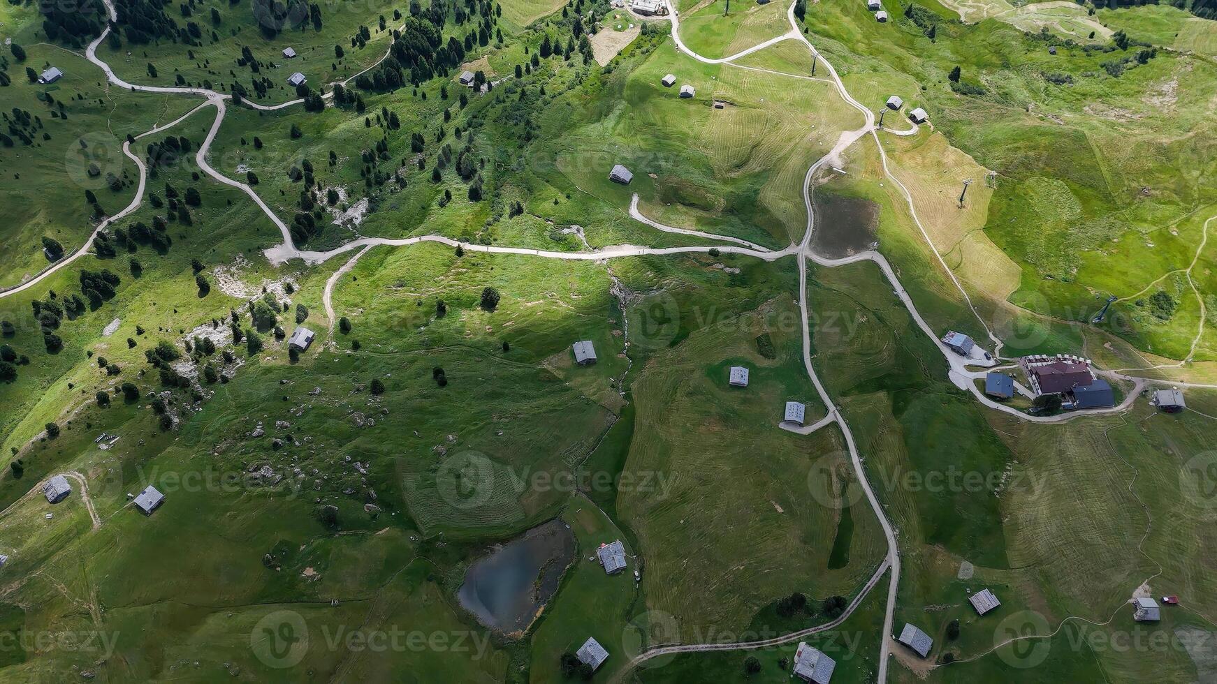Breathtaking aerial view of lush green mountain landscape dotted with quaint cabins during a serene summer day photo