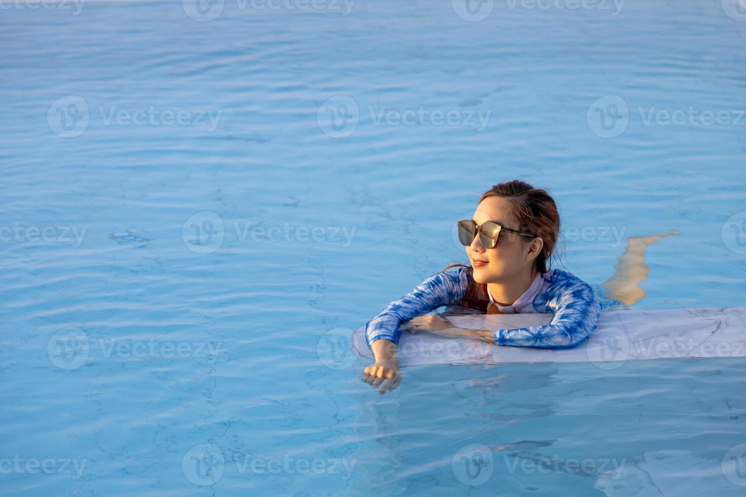 Asian woman is relaxingly swim in the hotel swimming pool for summer vacation and leisure holiday travel lifestyle photo