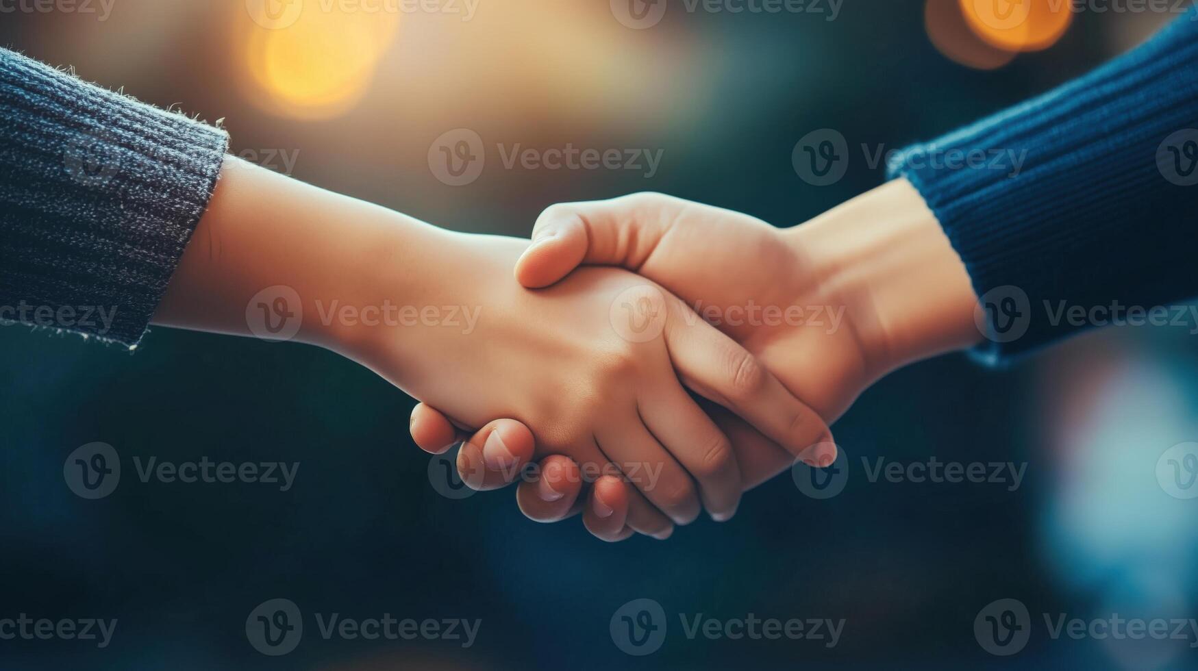 Close-up of two women shaking hands against dark background photo